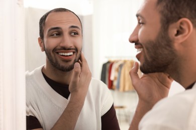 Photo of Smiling man looking at mirror at home