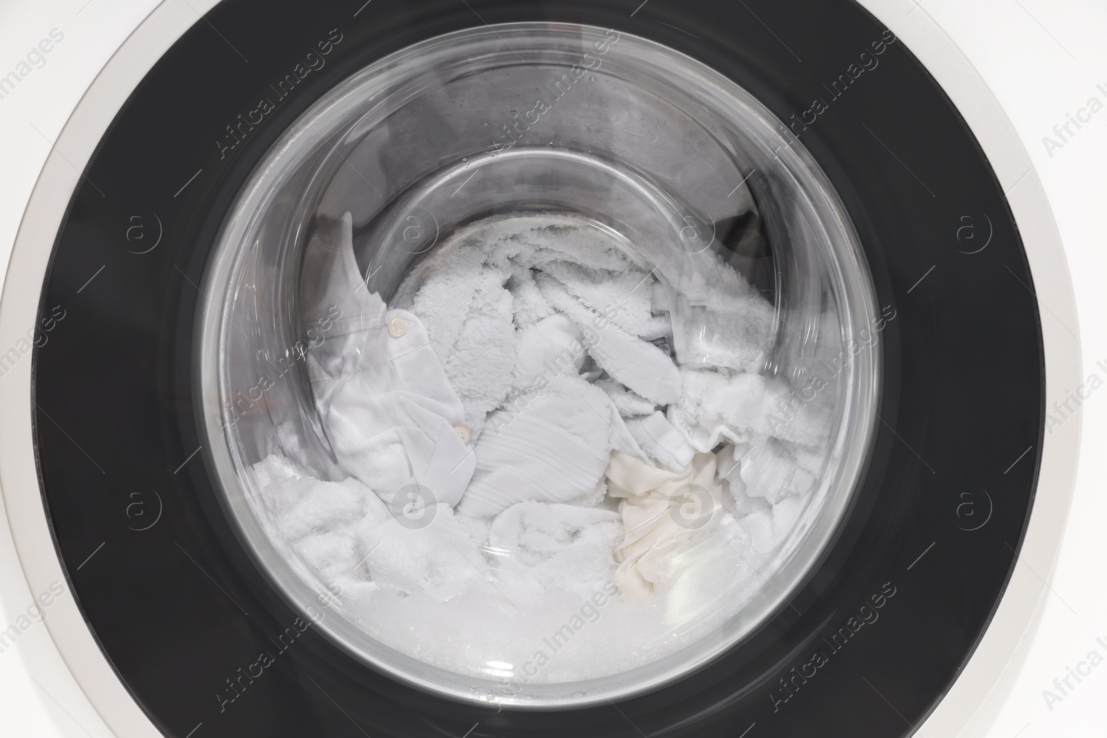 Photo of Washing machine with clothes as background, closeup