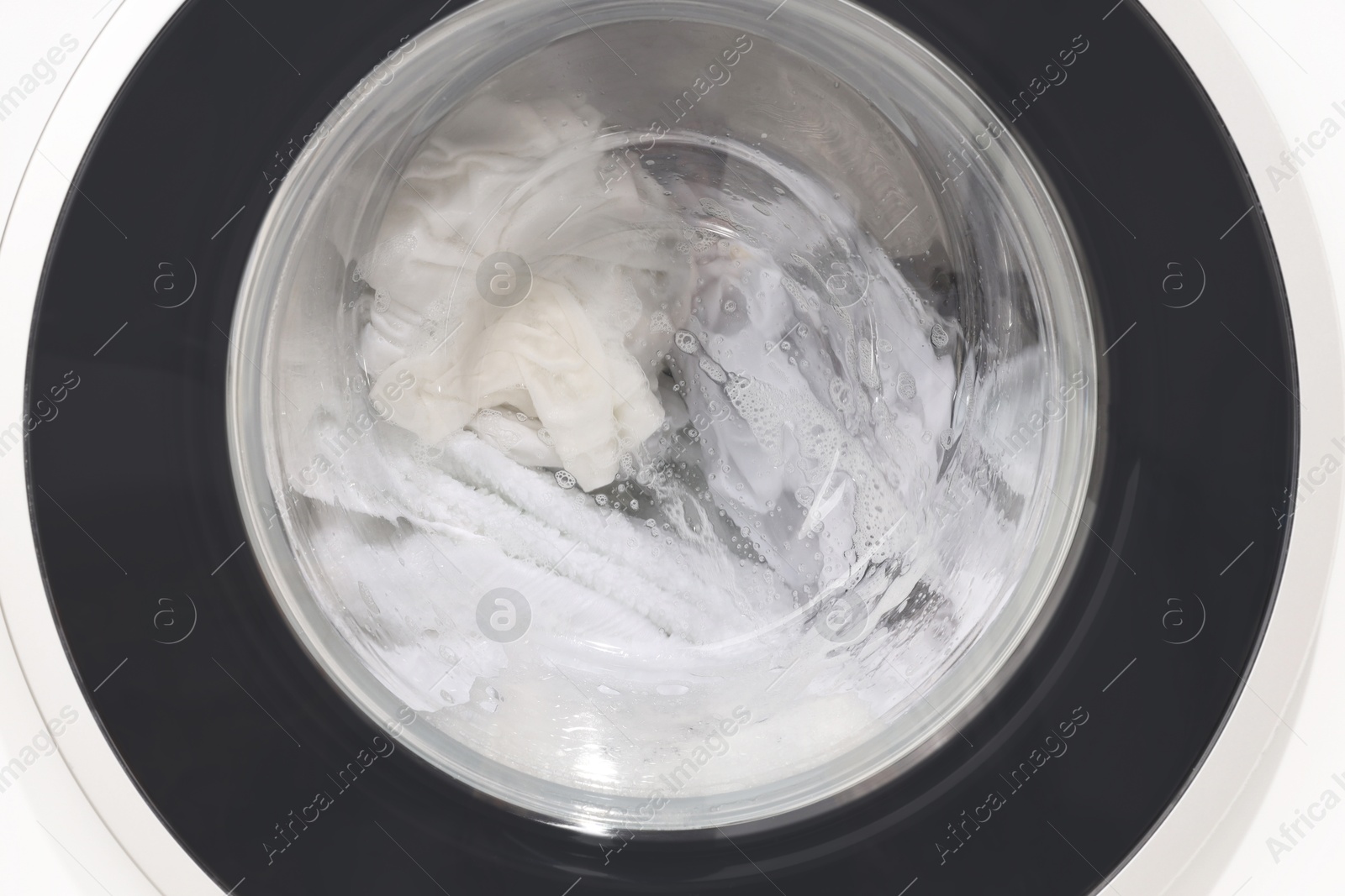 Photo of Washing machine with clothes as background, closeup