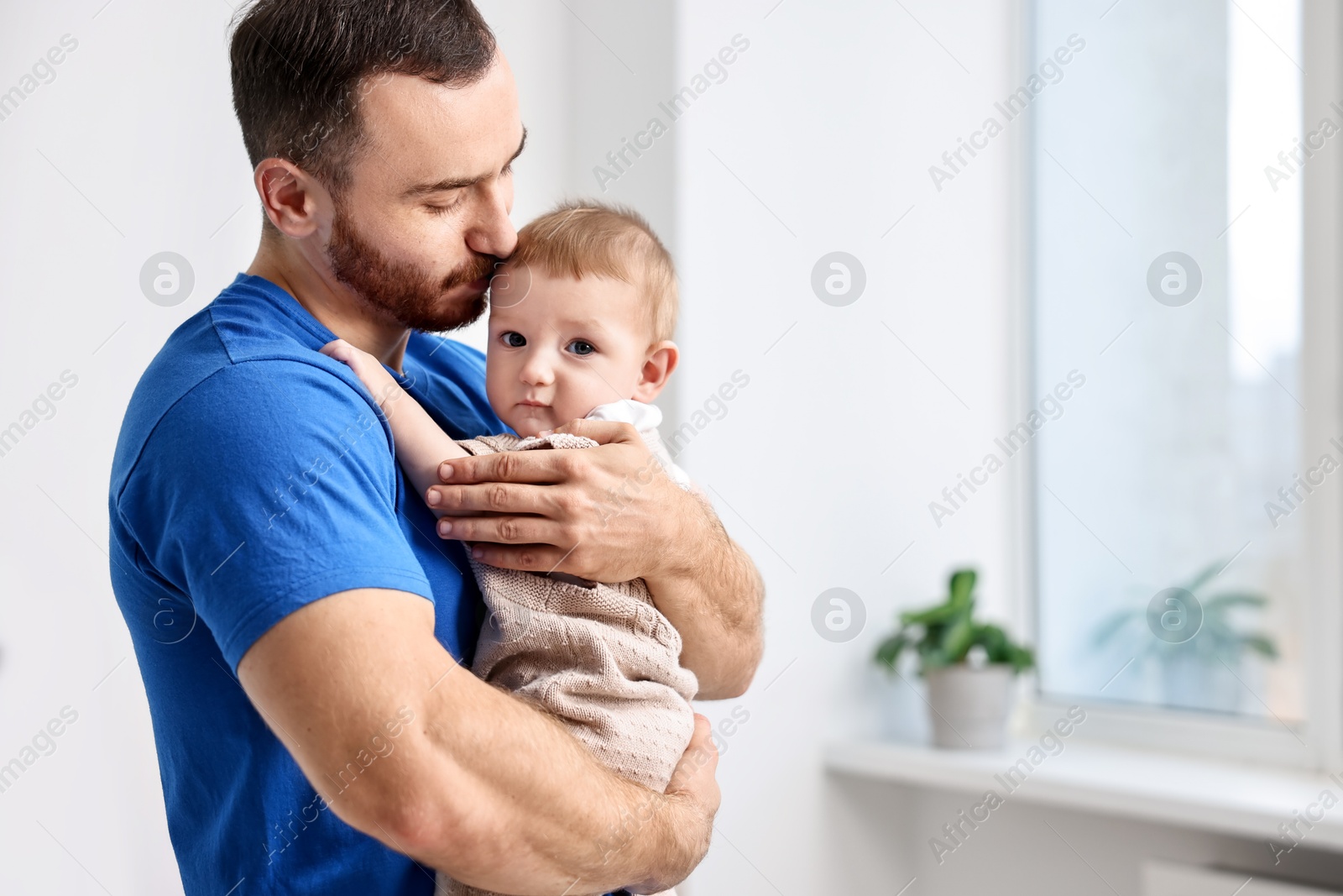 Photo of Dad with his cute little baby at home. Space for text