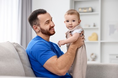 Photo of Father with his little baby on sofa at home