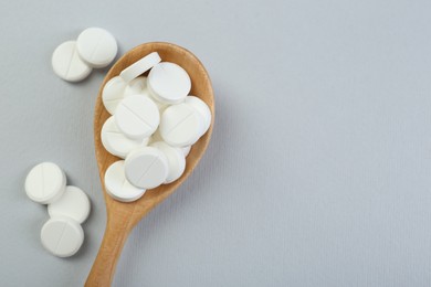 Photo of Antibiotic pills in wooden spoon on grey background, top view. Space for text