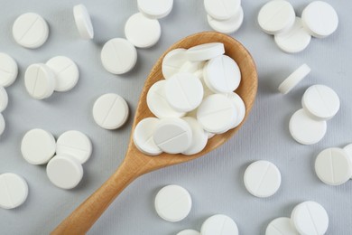 Photo of Antibiotic pills and wooden spoon on grey background, top view