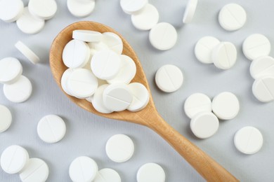 Photo of Antibiotic pills and wooden spoon on grey background, top view