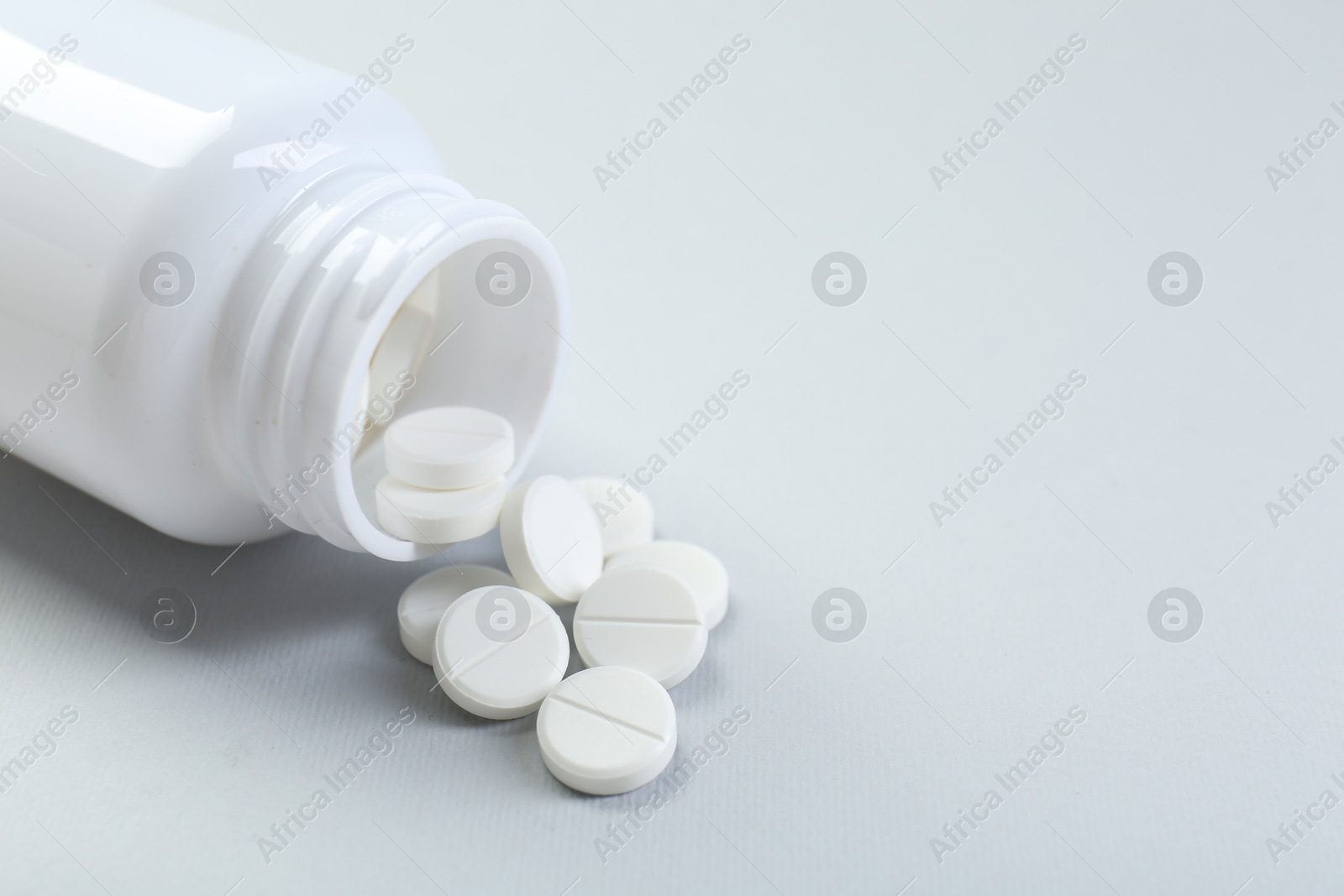 Photo of Medical bottle with antibiotic pills on grey background, closeup. Space for text