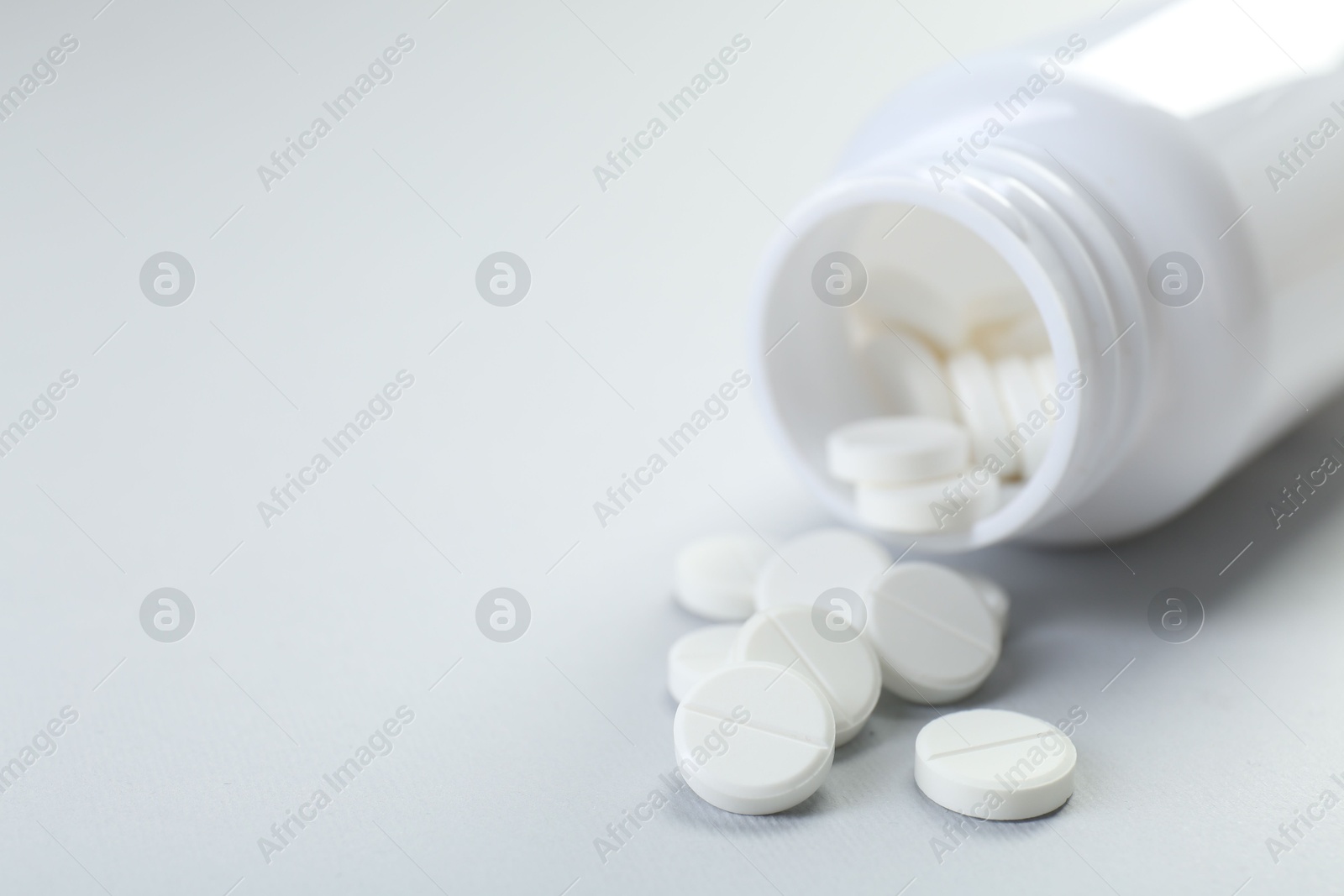 Photo of Medical bottle with antibiotic pills on grey background, closeup. Space for text