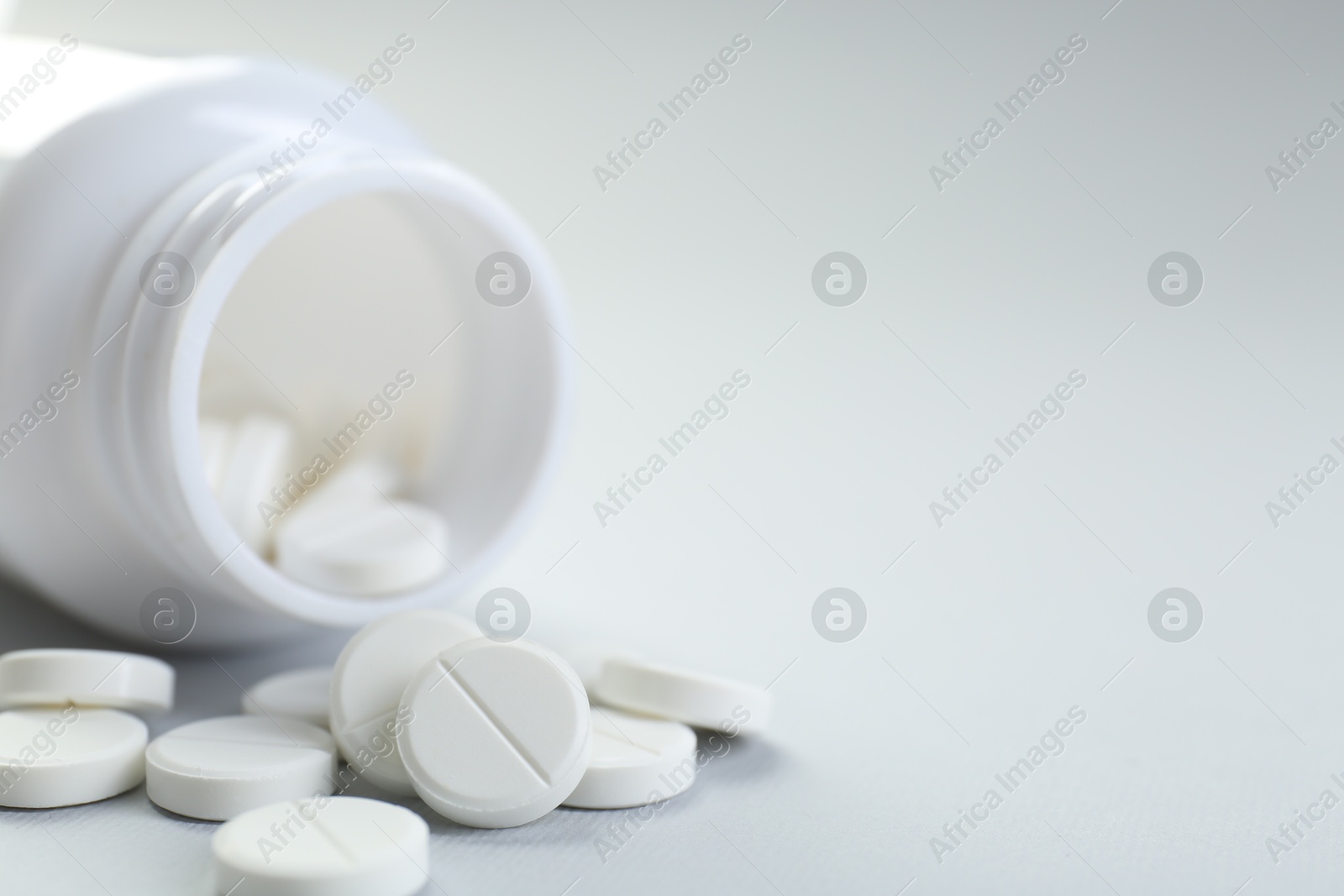 Photo of Medical bottle with antibiotic pills on grey background, closeup. Space for text