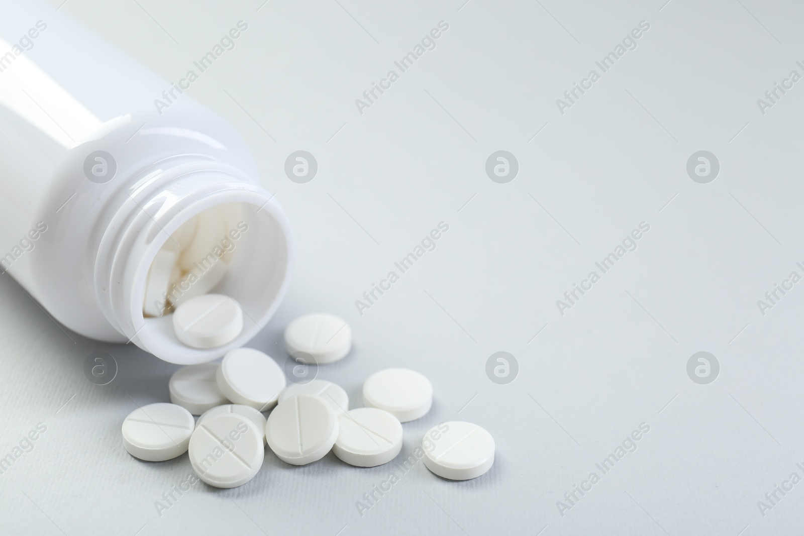 Photo of Medical bottle with antibiotic pills on grey background, closeup. Space for text