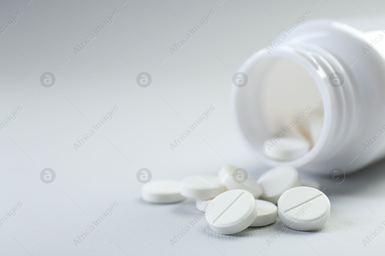 Photo of Medical bottle with antibiotic pills on grey background, closeup. Space for text