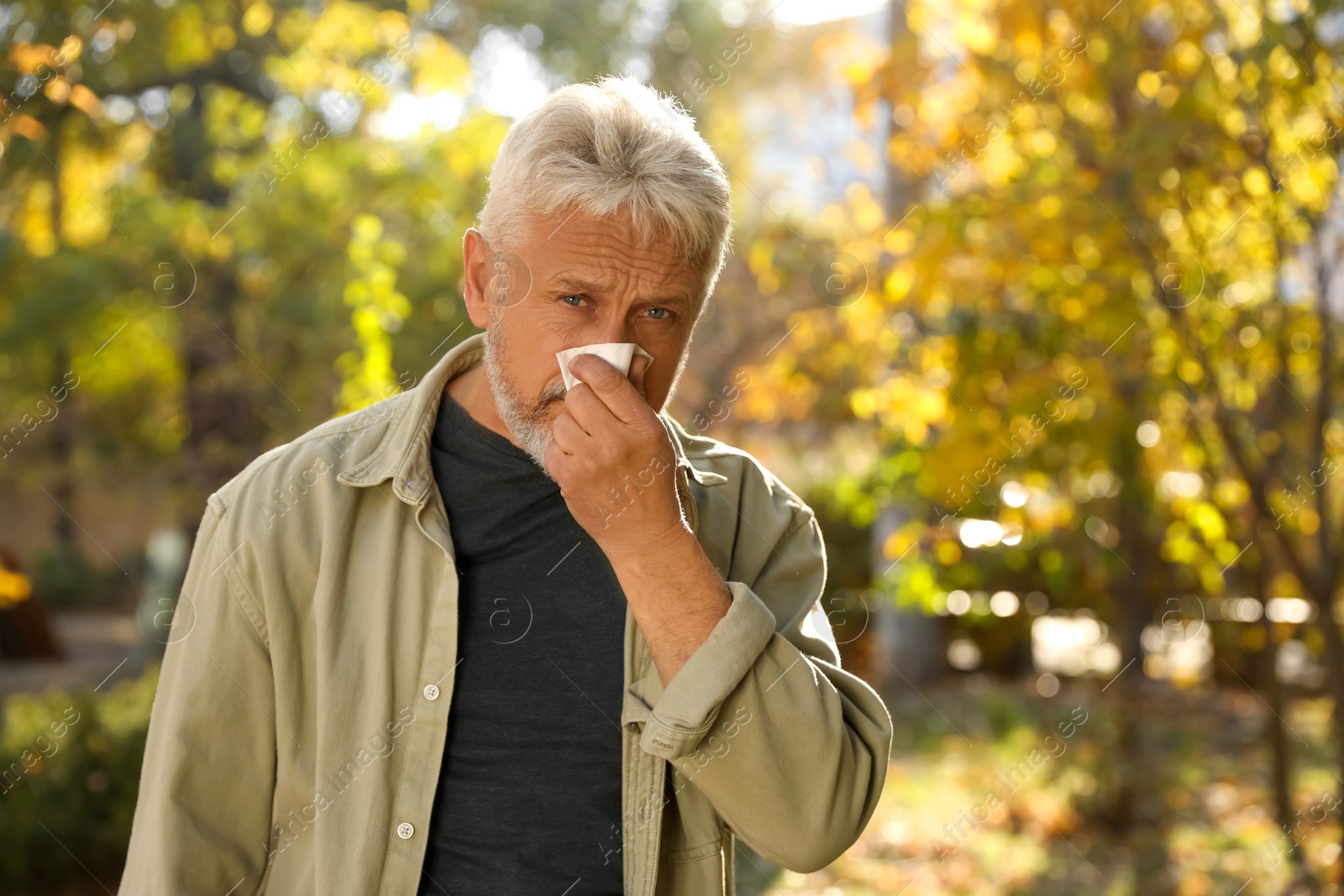 Photo of Senior man with runny nose in park, space for text