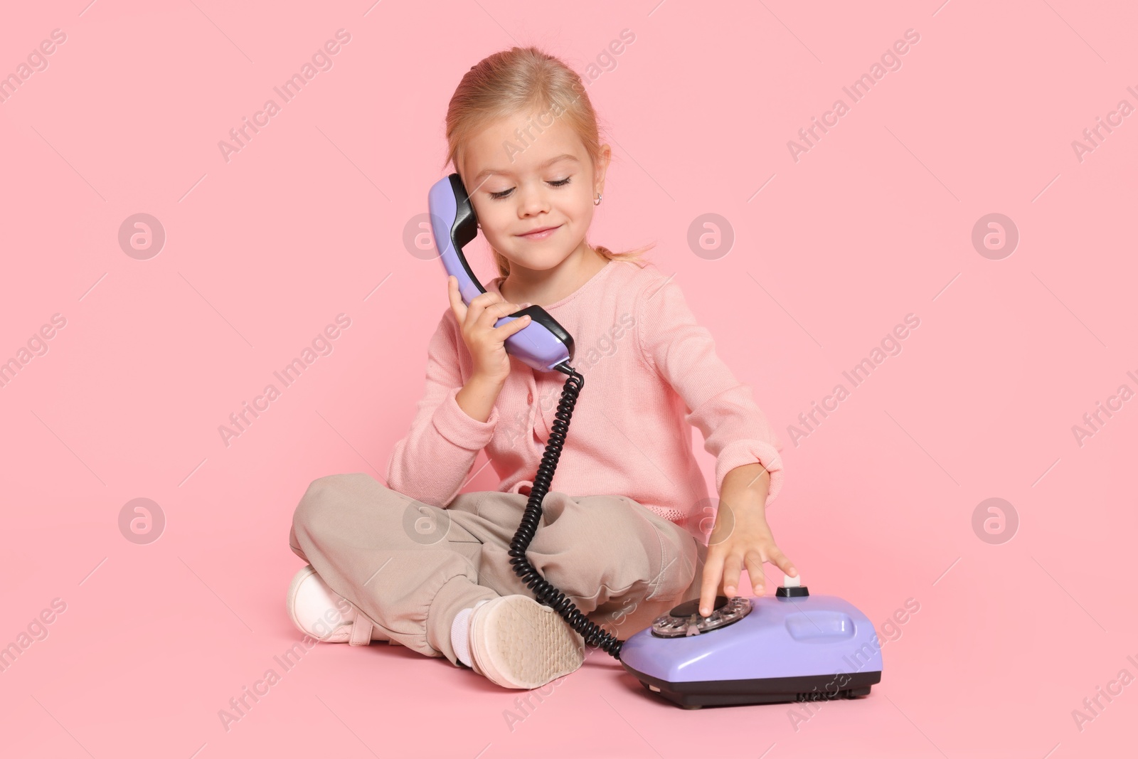 Photo of Cute little girl with telephone on pink background