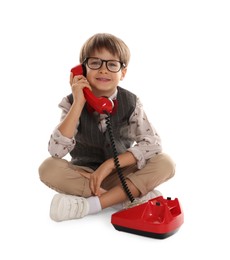 Cute little boy with old telephone on white background