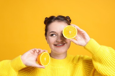 Photo of Happy young woman with halves of citrus fruit on orange background