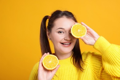 Photo of Happy young woman with halves of citrus fruit on orange background