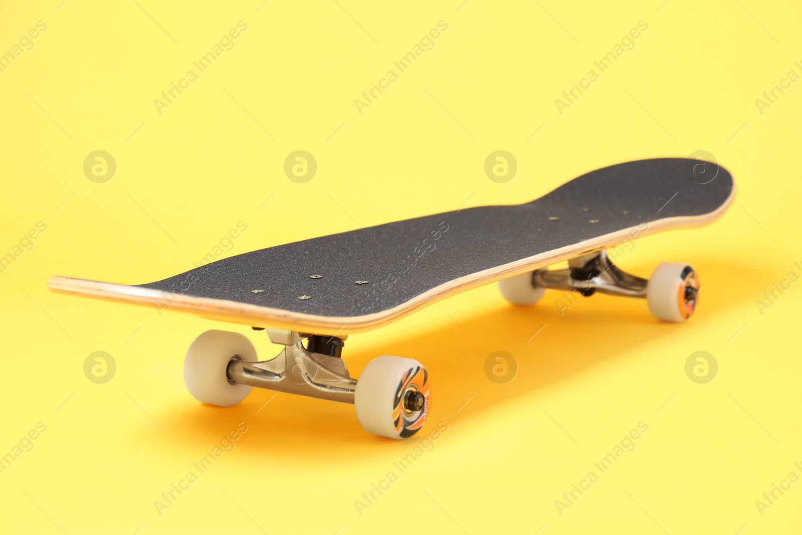 Photo of One skateboard on yellow background, closeup. Sports equipment