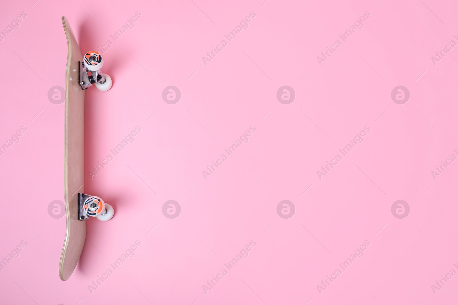 Photo of One skateboard on pink background, above view. Space for text