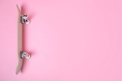 Photo of One skateboard on pink background, above view. Space for text