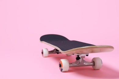 Photo of One skateboard on pink background, closeup. Space for text