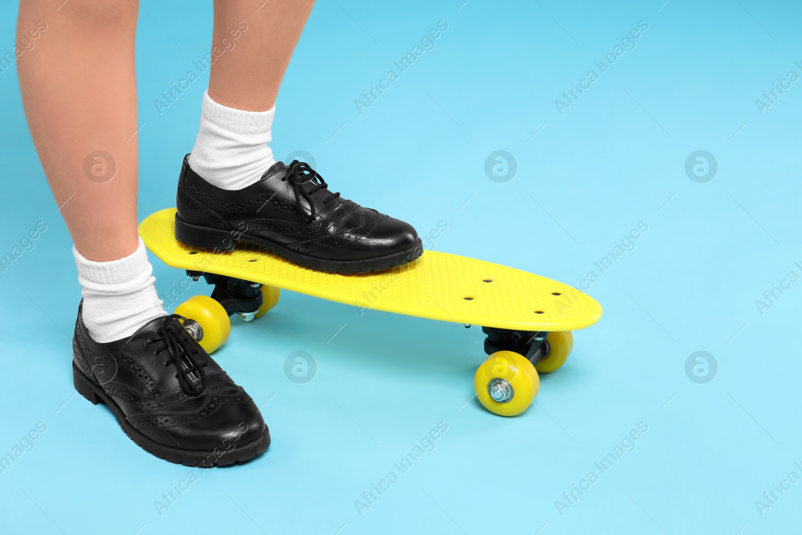 Photo of Little girl with penny board on light blue background, closeup