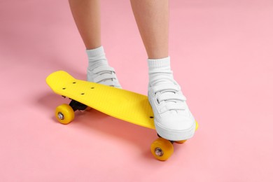 Photo of Little girl with penny board on pink background, closeup