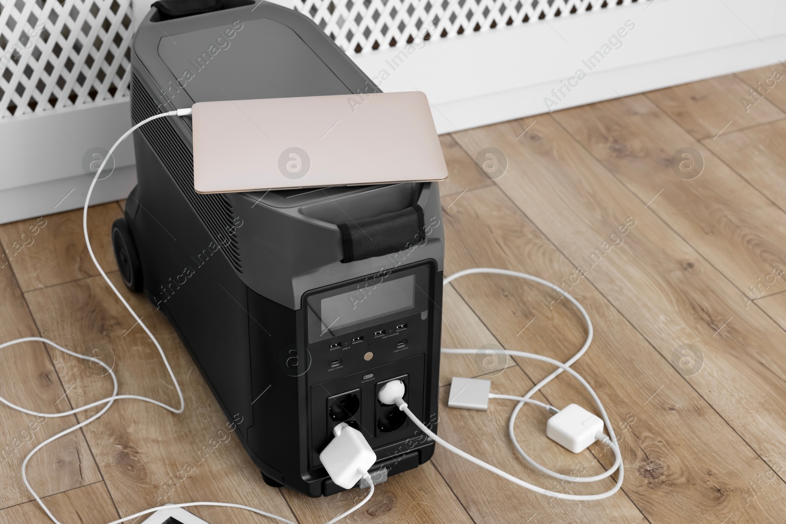 Photo of Modern portable power station, charging attached devices indoors, space for text