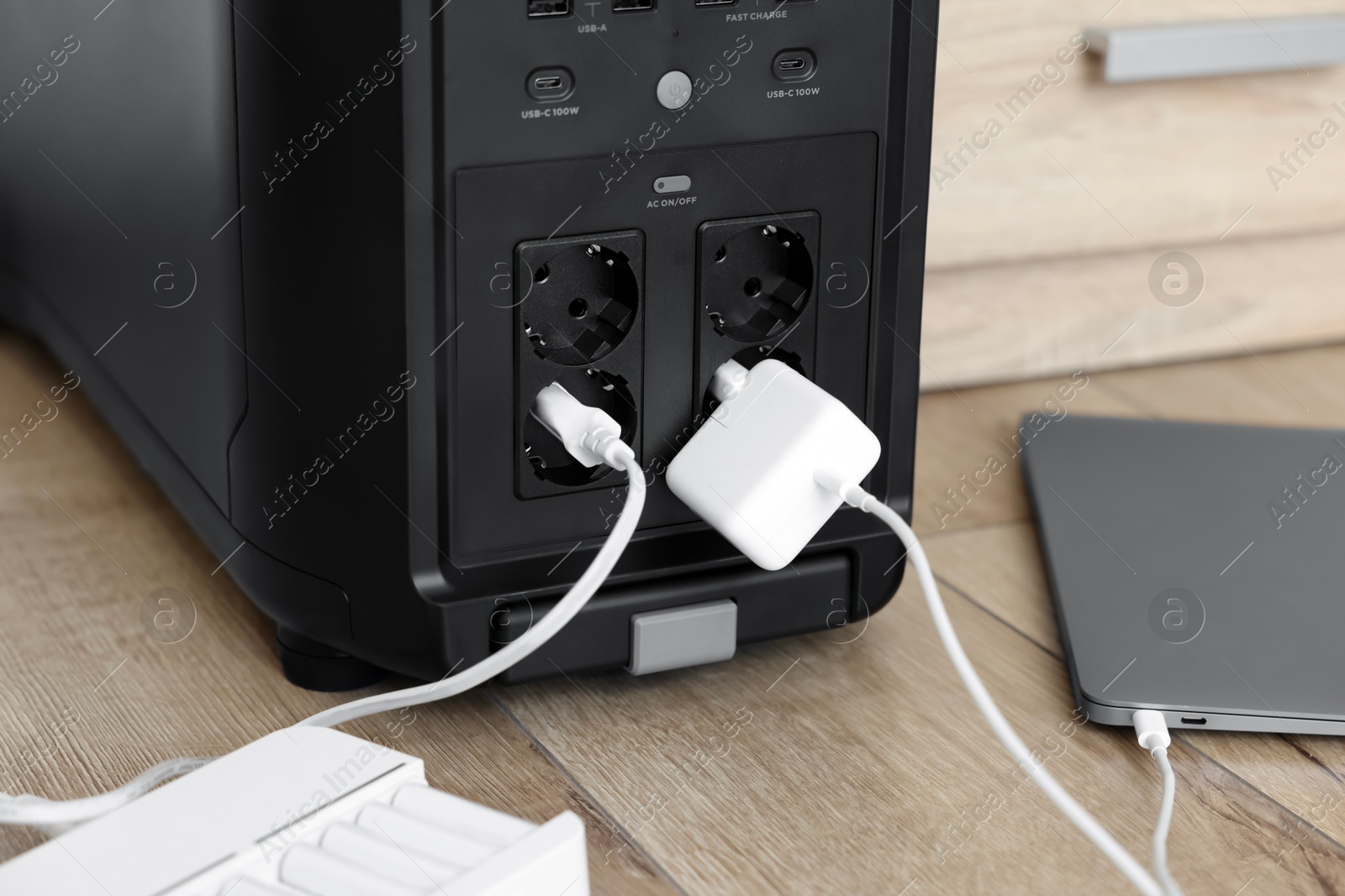 Photo of Modern portable power station, charging attached devices indoors, closeup