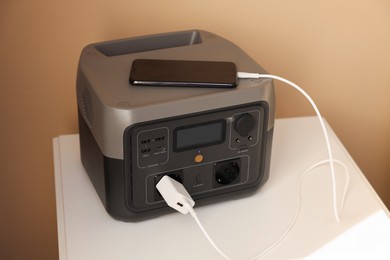 Photo of Smartphone charging from portable power station on nightstand indoors