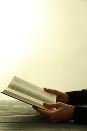 Woman with open Holy Bible in English language at wooden table, closeup