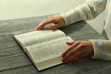 Woman with open Holy Bible in English language at wooden table, closeup