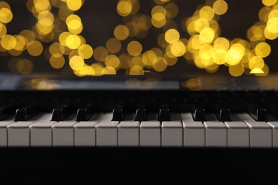 Photo of Piano against blurred lights, closeup. Bokeh effect