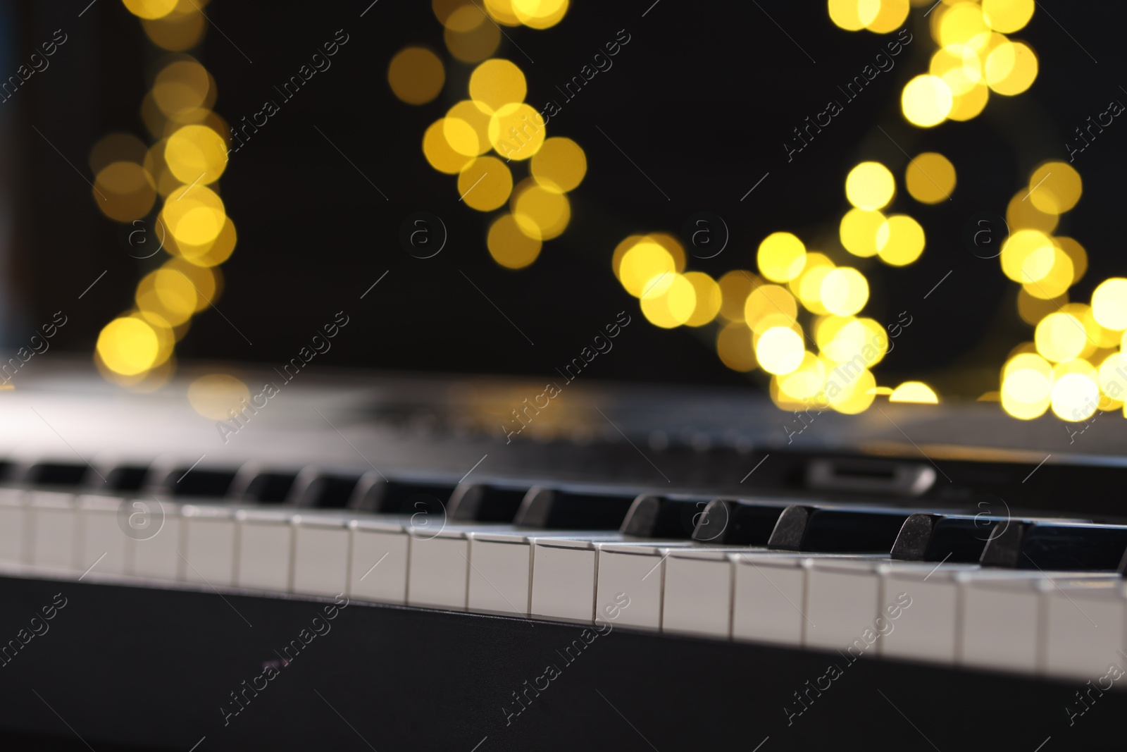 Photo of Piano against blurred lights, closeup. Bokeh effect