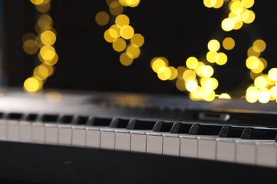 Photo of Piano against blurred lights, closeup. Bokeh effect