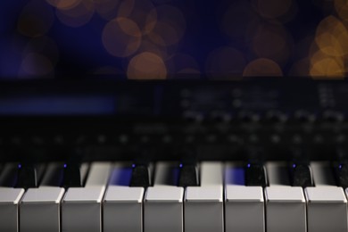 Photo of Piano against blurred lights, closeup. Bokeh effect