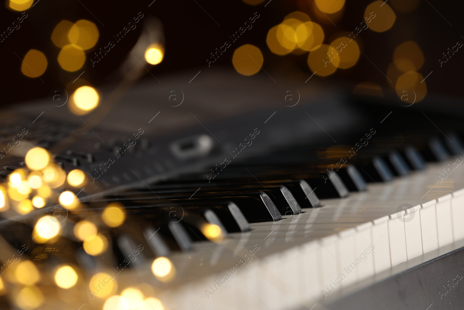 Photo of Piano against blurred lights, closeup. Bokeh effect