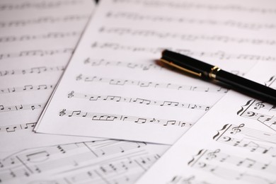 Photo of Sheets of musical notes and pen as background, closeup