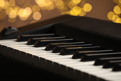 Photo of Piano against blurred lights, closeup. Bokeh effect