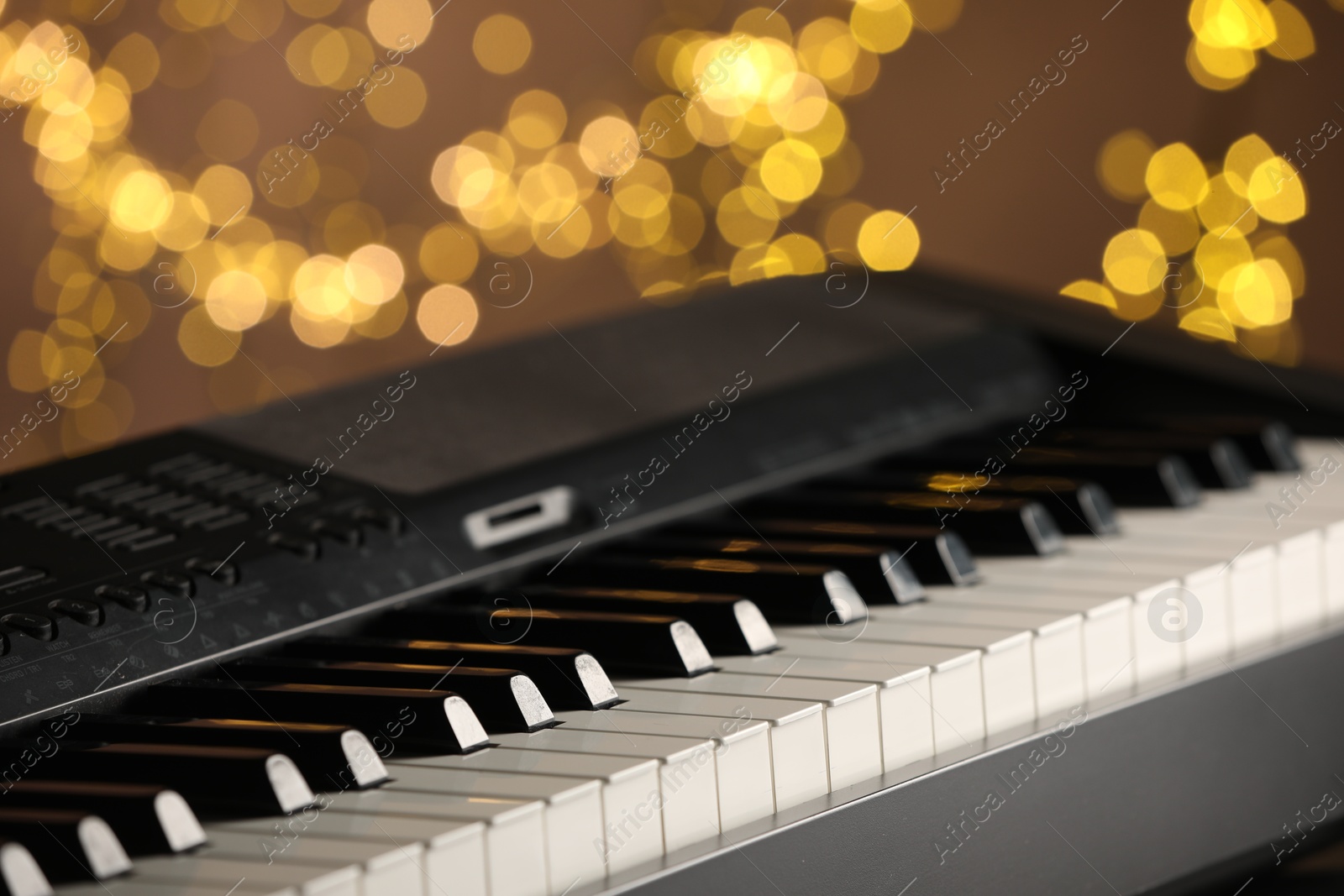 Photo of Piano against blurred lights, closeup. Bokeh effect