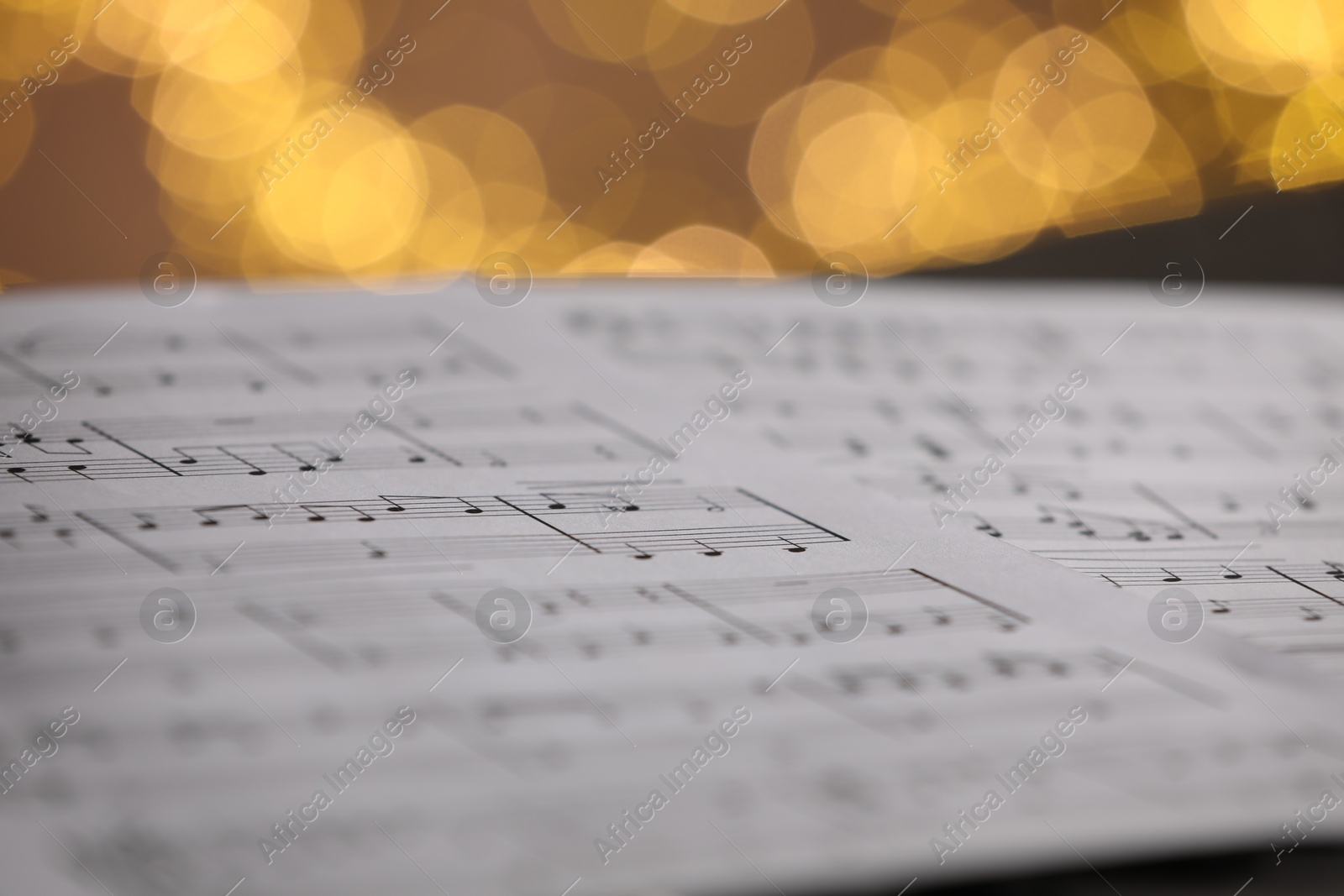 Photo of Sheet of musical notes against blurred lights, closeup. Bokeh effect