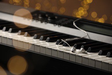 Photo of Earphones on piano against blurred lights, closeup. Bokeh effect