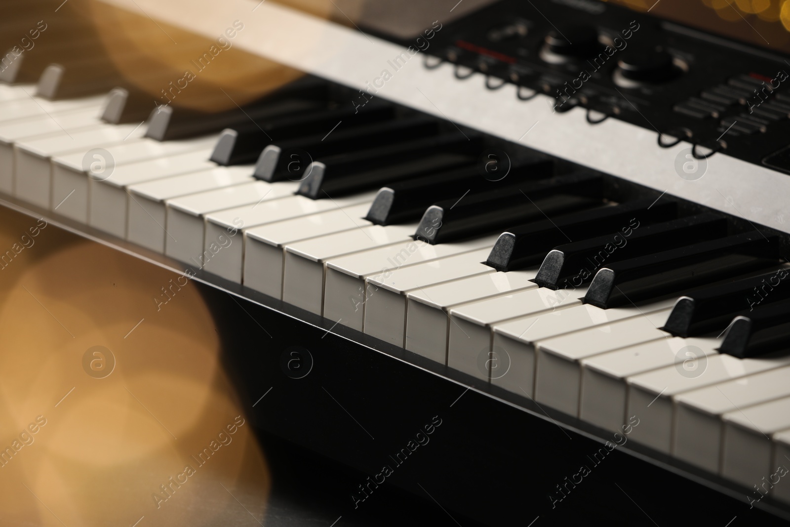 Photo of Piano against blurred lights, closeup. Bokeh effect