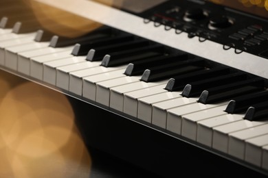 Photo of Piano against blurred lights, closeup. Bokeh effect