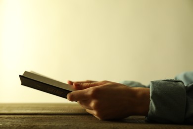 Woman reading Holy Bible at wooden table, closeup