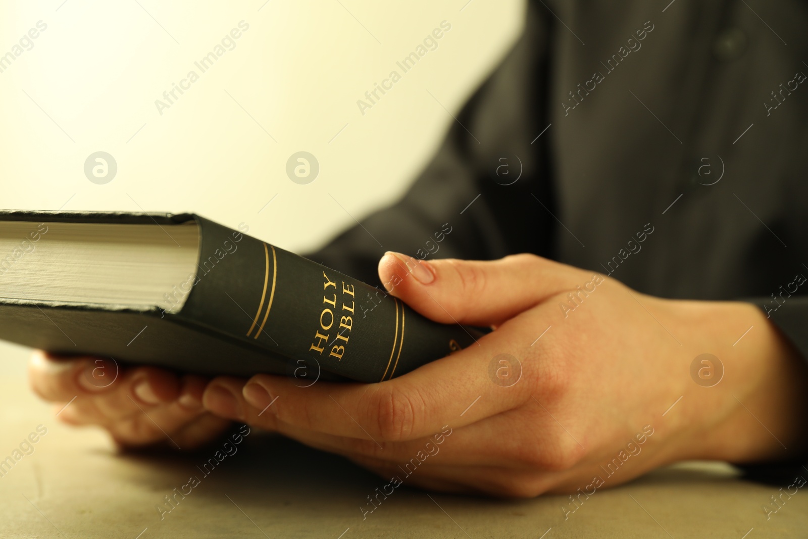 Photo of Woman with hardcover Holy Bible at beige table, closeup