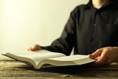 Woman with Holy Bible at wooden table, closeup