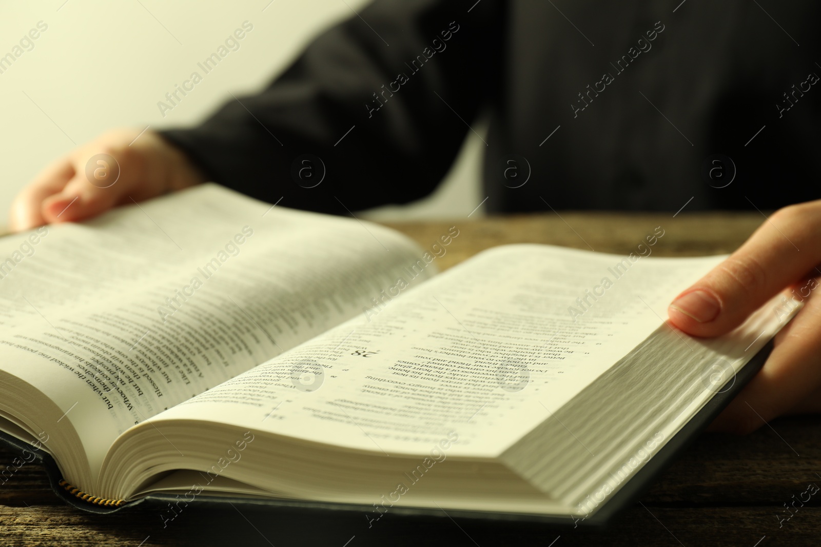 Photo of Woman with Holy Bible in English language at wooden table, closeup