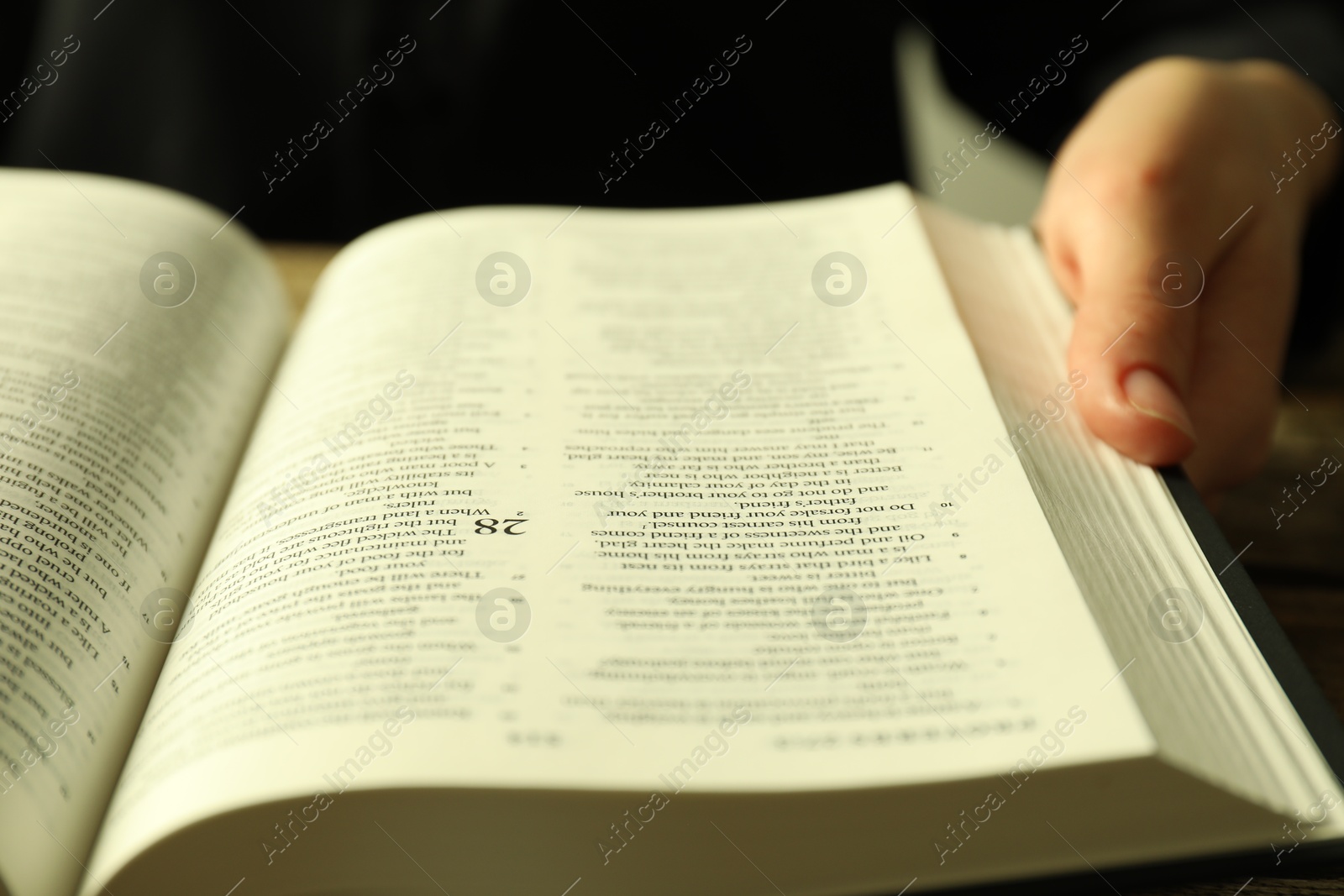 Photo of Woman with open Holy Bible in English language at table, closeup