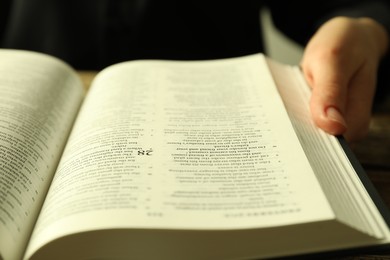 Woman with open Holy Bible in English language at table, closeup