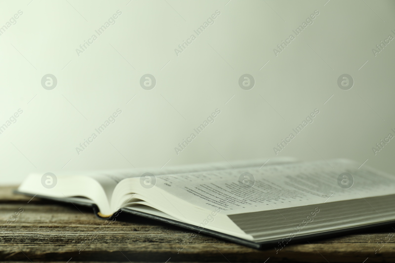 Photo of Open Holy Bible in English language on wooden table, closeup