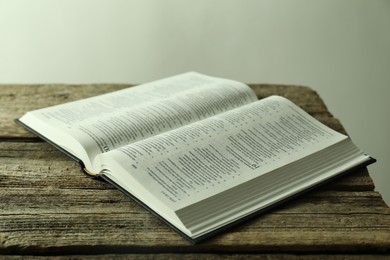 Photo of Open Holy Bible in English language on wooden table