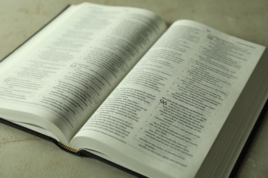 Open Holy Bible in English language on grey table, closeup